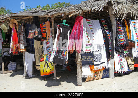 Cloths, robes, mats and towels sold by hawker on stall in open market on beach, Zanzibar, Unguja Island, Tanzania. Stock Photo