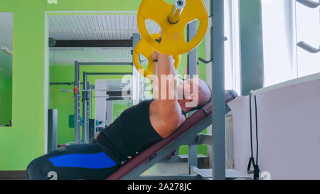 Athletic young man doing exercises with barbell at gym, fitness club Stock Photo