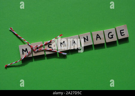 MisManage in 3d Wooden letters, with Mis crossed out, leaving the word Manage. Bright green background. Stock Photo