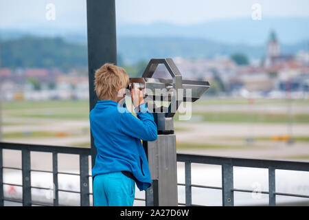 Boy looks through sights with public coin operated binoculars Stock Photo