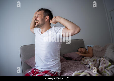 Young couple is sleeping in bed. Man is waking up for work. Stock Photo