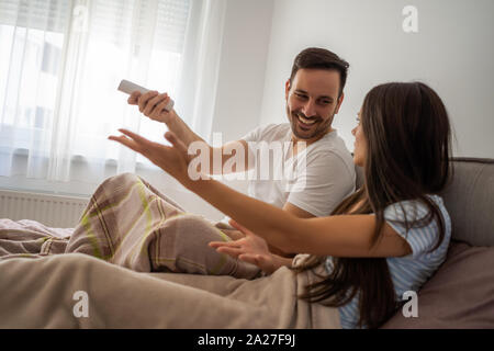 Young couple is watching tv in their bedroom. Stock Photo