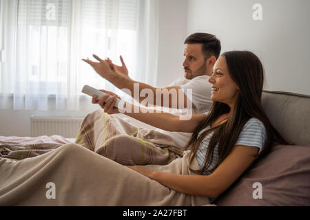 Young couple is watching tv in their bedroom. Stock Photo