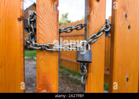 Padlock and steel thick chain on a bright yellow wooden fence Stock Photo
