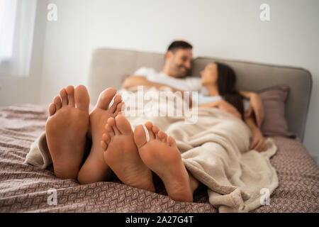 Happy couple is enjoying and relaxing themselves in bed. Stock Photo
