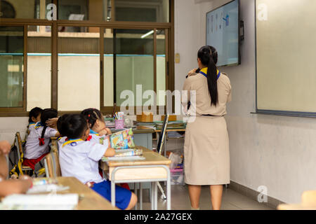 Back view of asian teacher stand in front of class and teaches students. Stock Photo