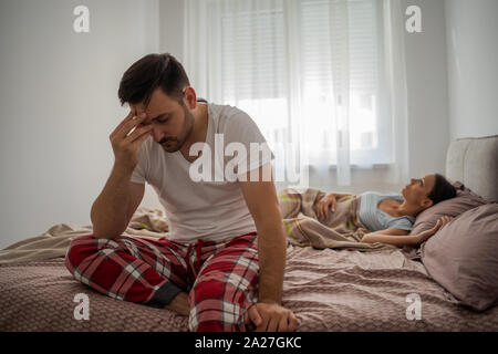 Young man is having insomnia. He wakes up early in the morning. Stock Photo