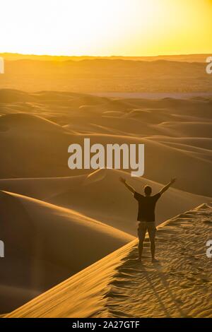 Man enjoying the sunset in the giant sanddunes of the Sahara, Timimoun, Algeria Stock Photo