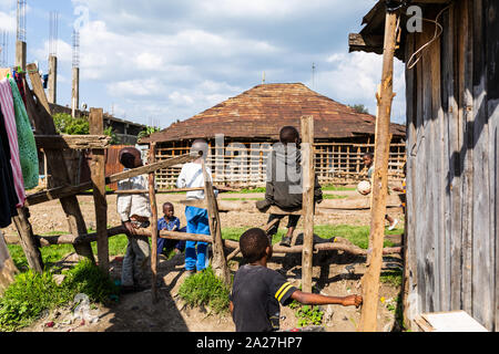 Nanyuki, Laikipia county, Kenya – June 19th, 2019: Impoverished Kenyan children sitting on-side of stone road in Kenyan suburb. Stock Photo