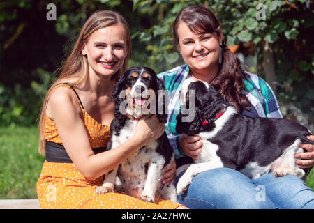 Two girlfriends having fun with dogs in the animal sanctuary Stock Photo