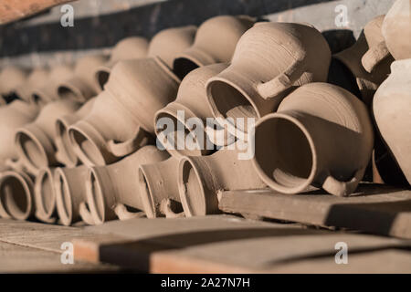 Fresh molded clay jars drying on a shelf in a potter's manufacturing studio.Local traditional craft and art concept Stock Photo