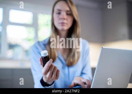 Woman At Home Looking Up Information About Medication Online Using Laptop Stock Photo