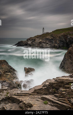 Trevose Head Lighthouse in North Cornwall with a stormy sky and waves crashing on the rocks makes a beautiful rugged landscape Stock Photo