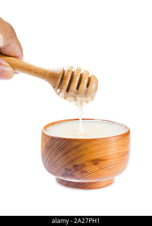 close up pouring condensed milk into wooden bowl isolated on white background, Save clipping path. Stock Photo