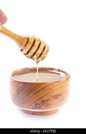 Honey scoop pouring caramel sauce in wooden bowl isolated on white background, Save clipping path. Stock Photo