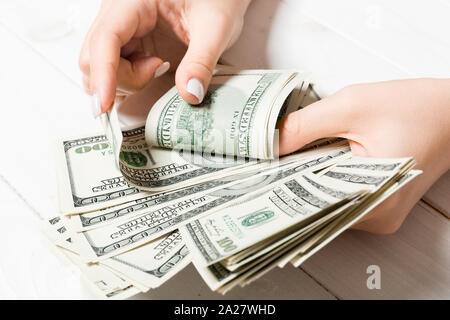 Businesswoman's hands counting one hundred dollar bills on wooden background. Salary and wage concept. Top view of Investment concept. Stock Photo
