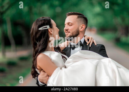 happy groom carries the bride in his arms Stock Photo