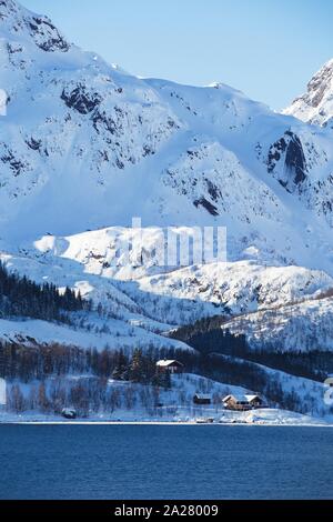 traditional norwegian wooden house to stand at the lakeside and mountains in the distance. Lofoten Islands. Norway. Stock Photo