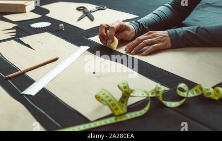 The tailor lays out the pattern on the fabric in the studio. The cutter outlines the pattern in the workplace. Stock Photo