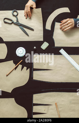 The tailor lays out the pattern on the fabric in the studio. The cutter outlines the pattern in the workplace. Stock Photo