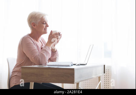 Senior lady enjoying cup of tea during working day Stock Photo