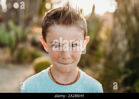 Close up portrait of cute young boy with freckles making serious face Stock Photo