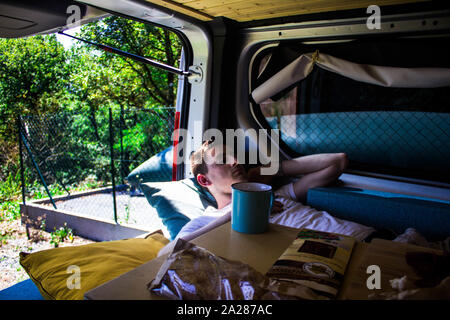 boy lying inside a caravan with the door open and food Stock Photo