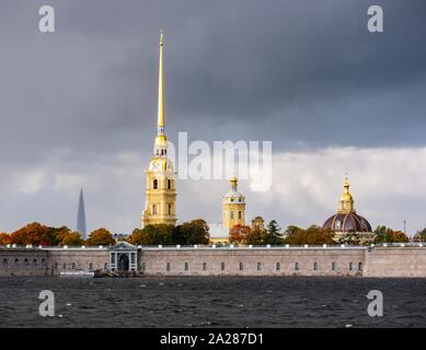 St Petersburg, Russia, 1st October 2019. Russia Autumn colours & weather: a dramatic sky with sunshine lighting up Autumn trees and the spires of Peter and Paul Cathedral in Peter and Paul Fortress seen across the Neva River Stock Photo