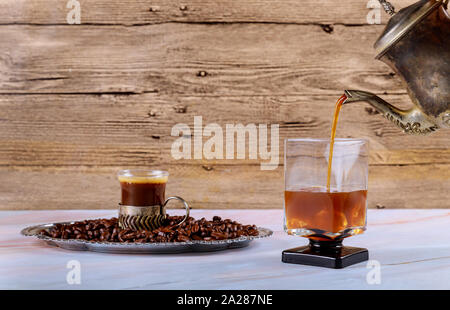 Pouring cold brew iced coffee from french press into the glass Stock Photo