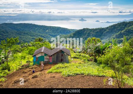 Farmer working in field in front of his home overlooking Taal Lake, Tagaytay, Cavite Province, Philippines Stock Photo