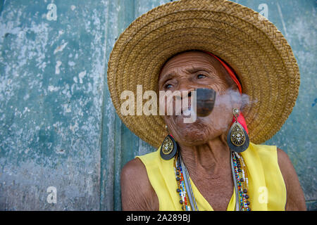 Senior Afro-Brazilian woman smoking pipe wearing straw hat Stock Photo