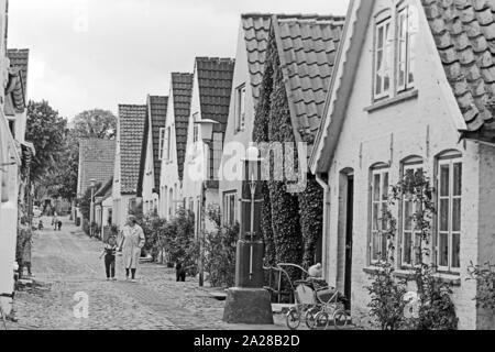 Straßenszene in einer kleinen Straße in Wyk auf der Insel Föhr, Deutschland 1960er Jahre. Street scene in a little lane at Wyk on Foehr island, Germany 1960s. Stock Photo