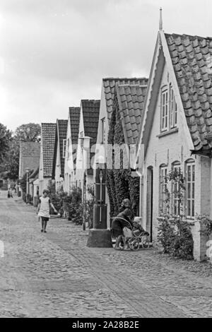 Straßenszene in einer kleinen Straße in Wyk auf der Insel Föhr, Deutschland 1960er Jahre. Street scene in a little lane at Wyk on Foehr island, Germany 1960s. Stock Photo