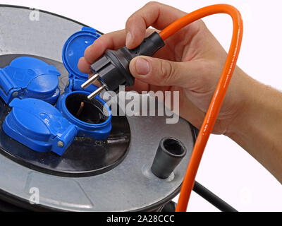 https://l450v.alamy.com/450v/2a28ccc/close-up-male-hand-is-plugging-orange-cable-in-cable-drum-electric-cord-reel-on-white-background-2a28ccc.jpg