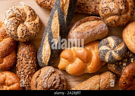 Background of mixed baguettes and bread rolls on light wood. Top view. Stock Photo