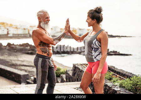 Fitness couple stacking hands during a workout day outdoor - Happy athletes motivating each other Stock Photo