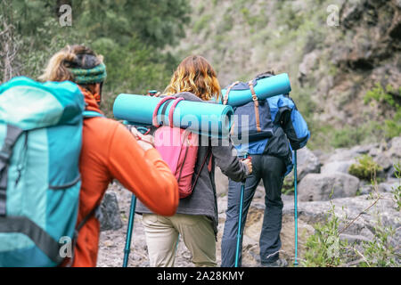 Group of people with backpacks doing trekking excursion on mountain - Young tourists walking and exploring the nature
