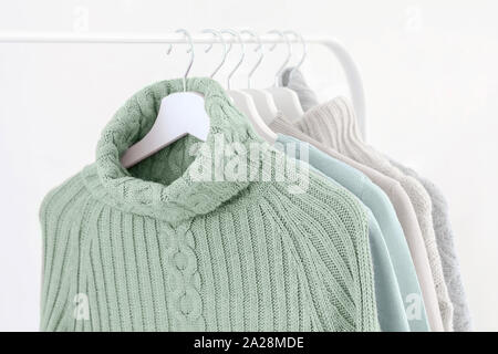 Tranquil mint green knitted warm sweaters on white hangers. Stock Photo