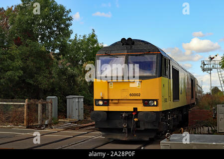 A yellow and black diesel loco crosses Bedlington level bringing bio mass wagon’s from Lynemouth power station. Stock Photo