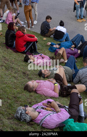 Munich, Germany, 2019 September 19: 4 mans sleeping in a row on the lawn at the Bavarian Oktoberfest in Munich Stock Photo