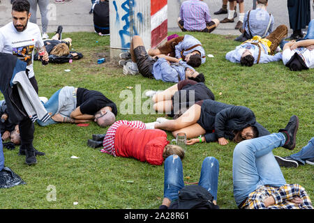 Munich, Germany, 2019 September 19: 4 mans sleeping in a row on the lawn at the Bavarian Oktoberfest in Munich Stock Photo