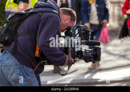 OSTRAVA, CZECH REPUBLIC – SEPTEMBER 22, 2019: Cameraman covers air show event, looks into the viewfinder of a broadcast camera. Stock Photo