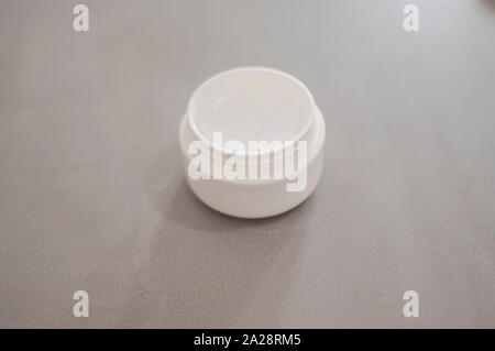 A beauty cream on a plastic container on a gray background