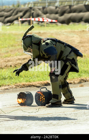 Bomb squad agent wearing a heavy blast suit disarms an explosive device. Stock Photo