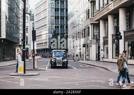 London, UK - September 07, 2019: Black cab waiting on traffic light on a road between modern office buildings in the City of London, London's famous f Stock Photo