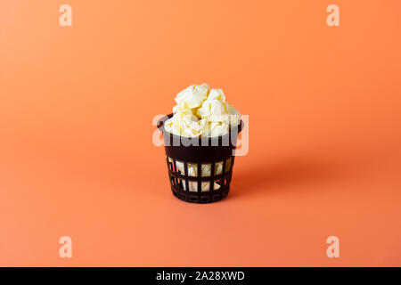 Recycle bin filled with crumpled paper on a bright orange background, recycling Stock Photo