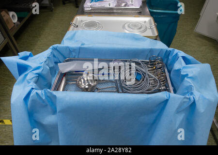 In a sterilization department in a hospital, cleaned instruments are wrapped in a blue cloth before the container is sterilized. Stock Photo