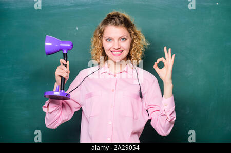 Insight and idea. Teacher hold table lamp chalkboard background. Knowledge day. Enlightenment concept. Creativity and inspiration. Turn light on. Proper light classroom. Light up process of studying. Stock Photo