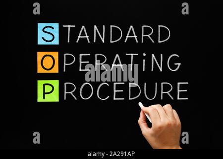 Hand writing SOP Standard Operating Procedure concept with white chalk on blackboard. Stock Photo
