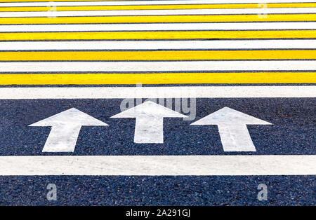 Pedestrian crossing with arrows, white and yellow stripes close up Stock Photo